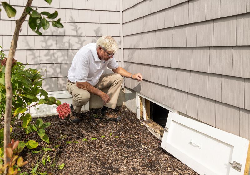 Technician checking a crawl space vent